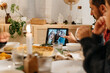© Sergio Marcos/Stocksy - Family having a videocall during christmas dinner