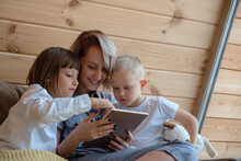 Mother And Kids Using Tablet On Sofa Together
