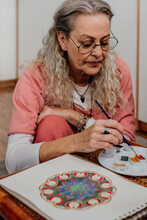 Close-up Of Senior Woman Painting Mandalas With Watercolors