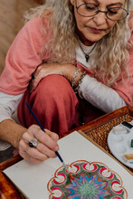 Portrait Of Senior Woman Painting Mandalas At Home