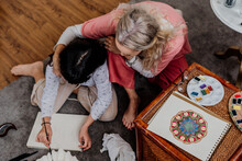 Grandmother Painting Mandala With Her Granddaughter At Bedroom 