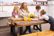 © VICTOR TORRES/Stocksy - Cheerful mother and children having breakfast on terrace