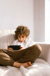 © VICTOR TORRES/Stocksy - Kid using smartphone on sofa