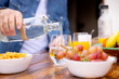 © VICTOR TORRES/Stocksy - Man pouring water into glass during breakfast