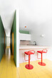 © Luciano Spinelli/Stocksy - Corridor and kitchen with two red stools in a colourful minimalist apartment