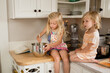 © Jennifer Bogle/Stocksy - Sisters stir batter on kitchen counter