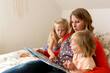 © Jennifer Bogle/Stocksy - Beautiful woman reads to daughters