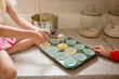 © Jennifer Bogle/Stocksy - Girl scoops muffin batter into tin