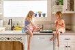 © Jennifer Bogle/Stocksy - Cute sisters perched on kitchen counter