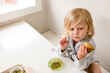 © Jennifer Bogle/Stocksy - Cute girl at table holds homemade muffin
