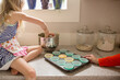 © Jennifer Bogle/Stocksy - Girl on counter scoops batter into tin