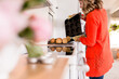 © Jennifer Bogle/Stocksy - Woman tips fresh muffins onto cooling rack