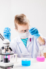 Wall Mural - a schoolboy with a microscope examines chemicals in test tubes, conducts experiments - a portrait on