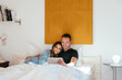 © David Prado/Stocksy - Optimistic couple using tablet on bed