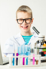 Wall Mural - a schoolboy with a microscope examines chemicals in test tubes, conducts experiments - a portrait on