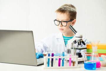 Wall Mural - schoolboy with a laptop in the laboratory conducts chemical experiments with substances in test tube