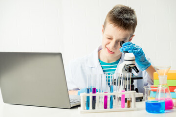 Wall Mural - schoolboy with a laptop in the laboratory conducts chemical experiments with substances in test tube