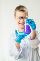 Wall Mural - a schoolboy studies multi-colored substances in test tubes, conducts experiments - a portrait on a w
