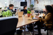 © Guille Faingold/Stocksy - Smart colleagues using laptops while working in creative workpla