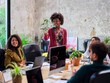 © Guille Faingold/Stocksy - Smiling Afro-American pointing at colleague.