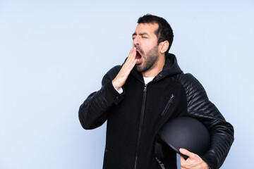 Man with a motorcycle helmet over isolated background yawning and covering wide open mouth with hand