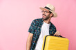 Young caucasian man over isolated background in vacation with travel suitcase and a hat