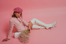 Fashionable, elegant woman wearing classic beret, pink tweed suit with mini skirt, white leather over knee boots with high heels. Full-length studio portrait. Copy, empty space for text