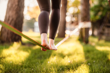 slacklining is a practice in balance that typically uses nylon or polyester webbing. girl walking on