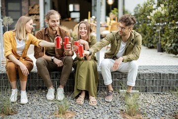 Wall Mural - Group of young friends spending summertime together, having fun while sitting in a row with drinks on a porch of the country house