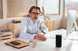 © BONNINSTUDIO/Stocksy - Mature freelancer talking to smart speaker