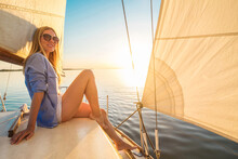 Young Happy Woman Enjoying Sunset From Deck Of Sailing Boat Moving In Sea At Evening Time. Travel, Summer, Holidays, Journey, Trip, Lifestyle, Yachting Concept.
