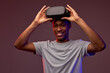 © Roman - Excited african american man looking at you with smile while taking off vr headset after looking through virtual assortment, experienced virtual reality game, isolated on vinous background