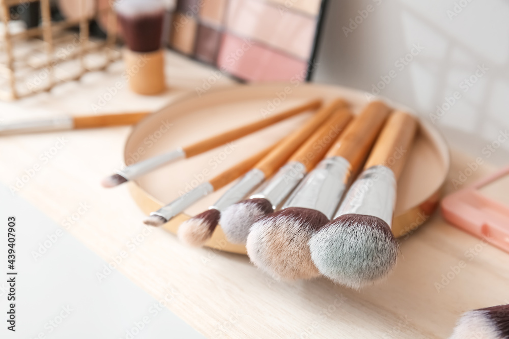 Tray with set of makeup brushes on table, closeup