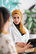 © Studio Marmellata/Stocksy - Positive Moroccan woman listening to colleague in office