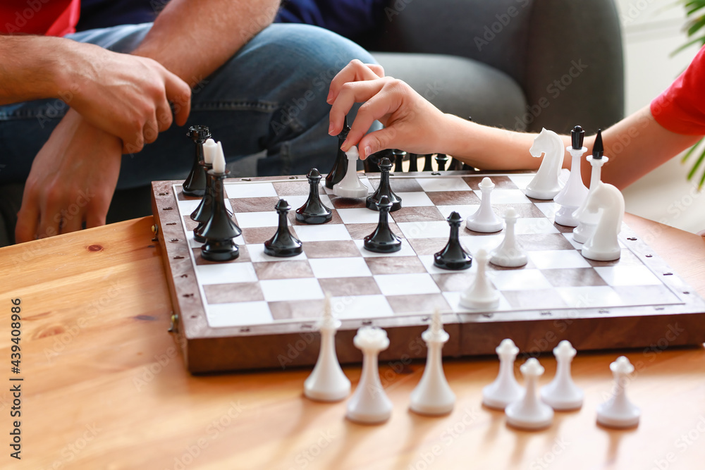 Father and son playing chess at home, closeup