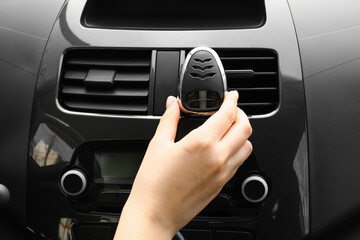 Female hand with air freshener hanging in car, closeup