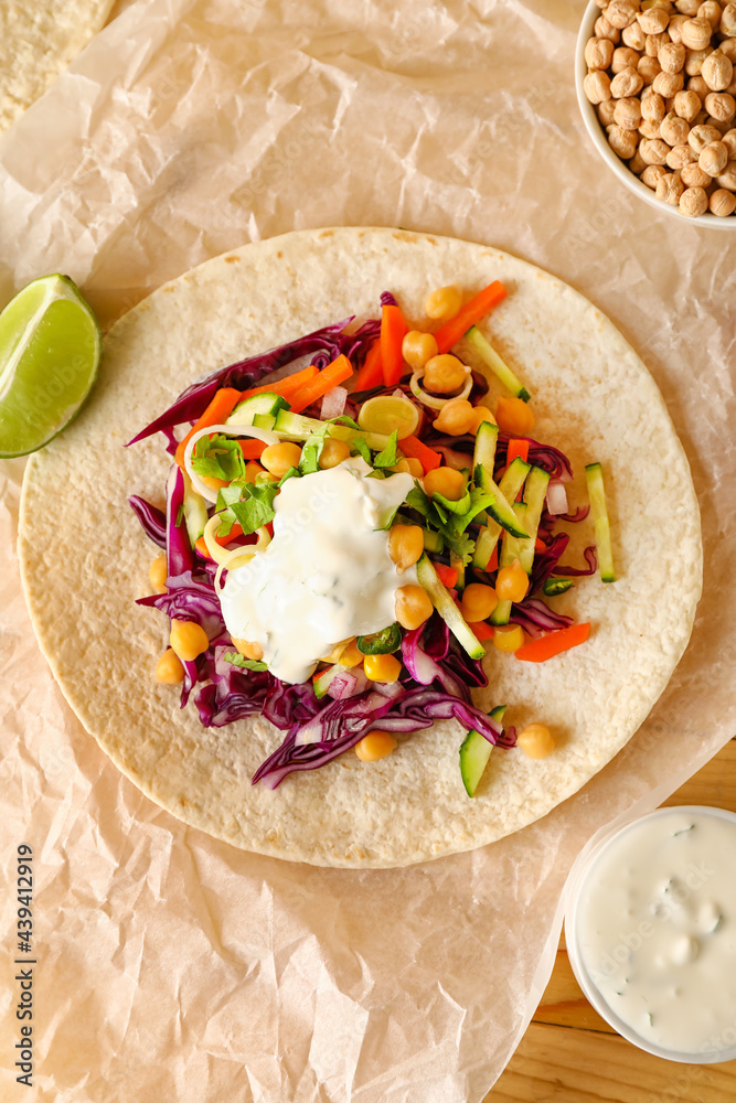 Parchment with tasty vegetarian taco on table