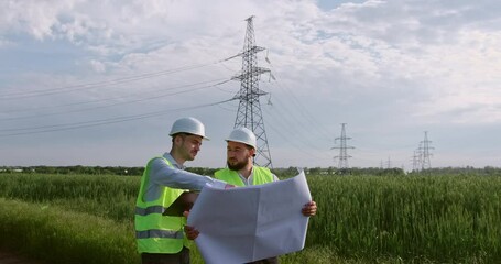 Wall Mural - two engineers discuss a drawing on paper in the open air against the background of a high-voltage po