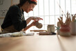 © Malquerida Studio/Stocksy - Ceramist young woman Making Clay cups  in her studio