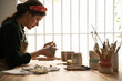 © Malquerida Studio/Stocksy - Ceramist young woman Making Clay cups  in her studio