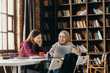 © Stereo Shot/Stocksy - Positive diverse students studying in library with laptop