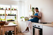 © BONNINSTUDIO/Stocksy - Black gardener reading book in kitchen
