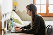 © Nuria Seguí/Stocksy - Young woman with headphones working on the laptop at her home office