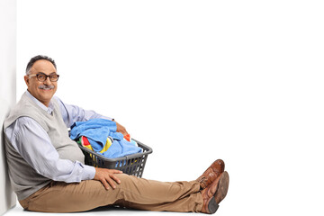 Sticker - Smiling mature man sitting and holding a laundry basket