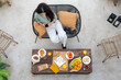 © Bisual Studio/Stocksy - Woman using smartphone during breakfast on terrace