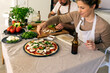 © Valentina Barreto/Stocksy - couple cooking pizza at home