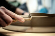 © Albert Martinez/Stocksy - Person filing a ceramic piece ina workshop
