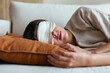 © BONNINSTUDIO/Stocksy - Woman in sleeping mask relaxing on sofa
