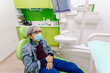 © ByLorena/Stocksy - Boy in mask sitting in contemporary dental office