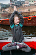 © Amanda Voelker/Stocksy - A little girl practicing yoga on a boat in the ganges